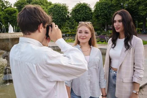 Guy taking shot of his two female friends near fountain 스톡 사진