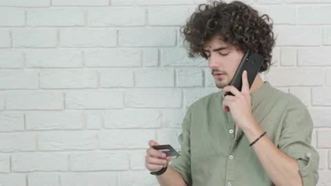 Guy talking on phone and reading credit card number while working. Stock Footage 169399960