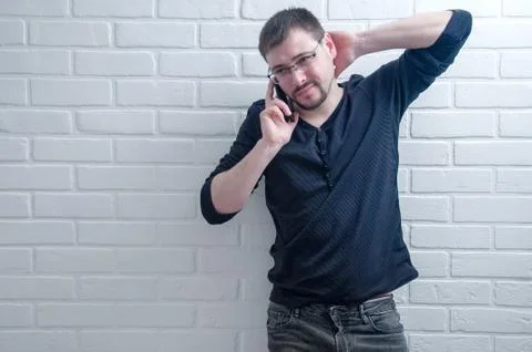 The guy is talking on the phone on the background of a white loft. Foto stock