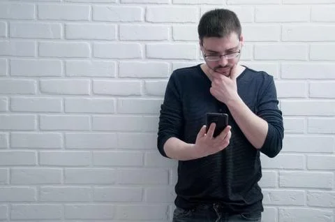 The guy is talking on the phone on the background of a white loft. Stock Photos