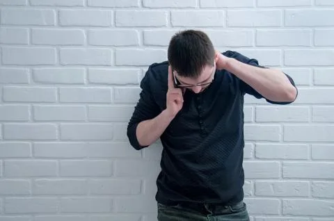 The guy is talking on the phone on the background of a white loft. Foto stock