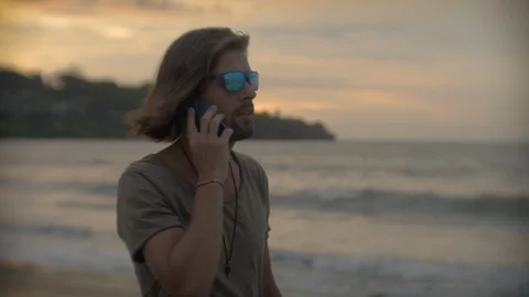 Guy talking on the phone on the beach Stock Footage 105934074