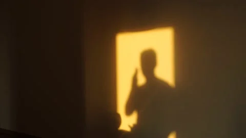 The guy is talking on the phone at home. Dark silhouette of sun shadow Stock Footage 156905076