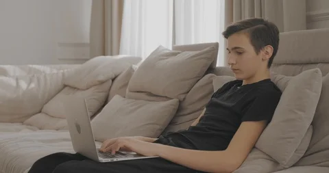 Guy talking on the phone sitting on the couch at home. Young man sitting on s Stock Footage 106088253