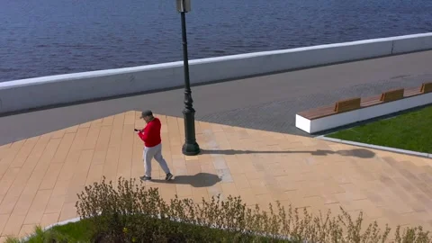 A guy is talking on a smartphone and walking along the promenade Stock-Footage 131417123