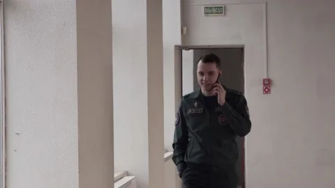 The guy talks in a fire uniform over the phone. In a buiding. Stock Footage 130222346