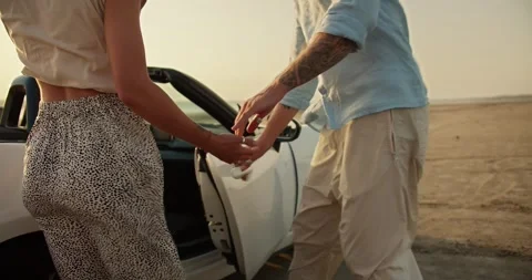 A guy with a tattoo on his arm in a blue shirt opens the door of a white Видео 250078028
