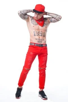 Guy with tattoos in red jeans and a cap with a red kerchief around his neck a Stock Photos