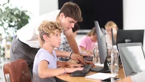 Guy teacher teaches boy student to work with computer Stock Footage 312228474
