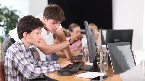 Guy teacher teaches boy student to work with computer Stock Footage 331294274