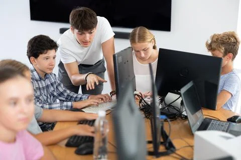 Guy teacher teaches boy student to work with computer Stock Photos