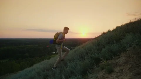 The guy the teenager with a backpack climbs up the mountain. At sunset. Active Stock Footage
