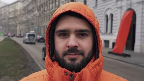 The guy with the thick beard in the hood looks at the camera and smiles Video stock 105684402