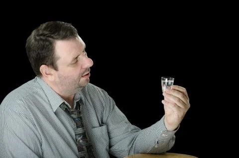 Guy thinks to drink one more vodka shot 库存照片
