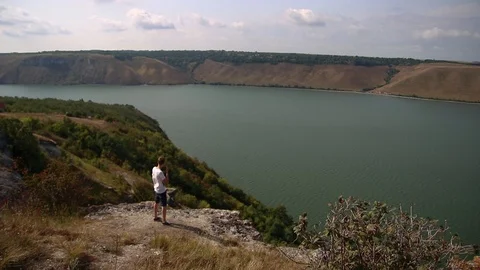 Guy thinks on rocks, lake, adventure time, nature Stock Footage 94485424