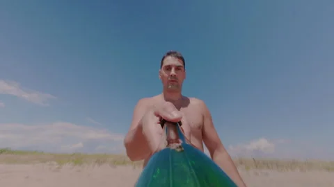 The guy throws and catches a bottle on the beach. Stock Footage 339931390