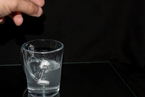 The guy throws effervescent tablets into a glass of water Stock Photos