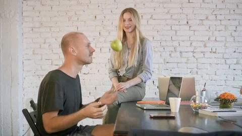 A guy throws a green apple and a business girl catches him at the office Stock Footage 91593491