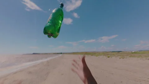 A guy throws a plastic water bottle on the beach.From the first person. Stock Footage 341347600