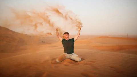 The guy throws sand over himself in the desert. The desert is next to Dubai. UAE Stock Photos