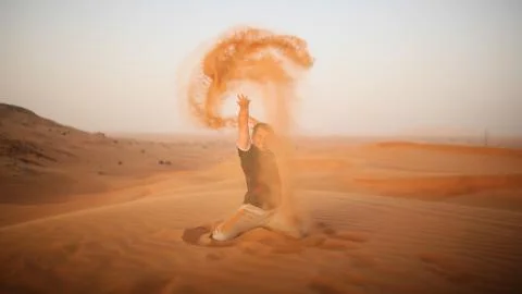 The guy throws sand over himself in the desert. The desert is next to Dubai. UAE Stock Photos