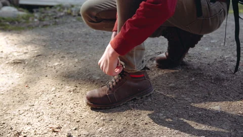 The guy ties the laces on brown boots standing on one knee on the ground. Stock Footage 195205474