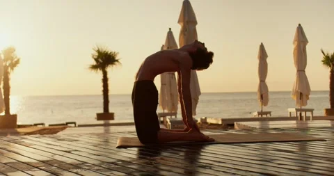 The guy took a pose during a yoga class. He touches his fingers to his heels Видео 249235338