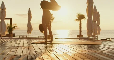 The guy took a pose during a yoga class. He stands on his hands, holding his Stock Footage 249844284