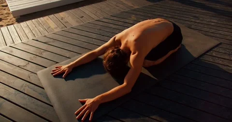 The guy took a special pose for yoga and stretching on a special mat on a sunny Видео 249844028