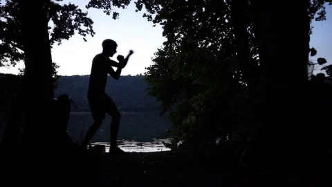Guy training after sunset, battle with the shadows, training in nature Stock Footage 114631344