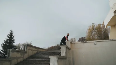 The guy is training parkour. Jumps on the railing on a cold autumn day. Does a Stock Footage 120240562