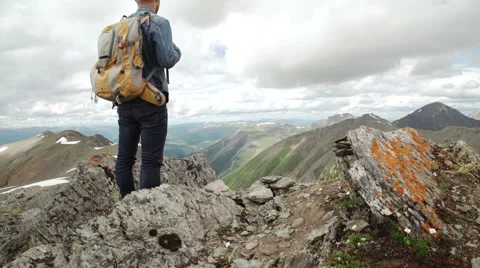 Guy with a travel backpack on the top of a boulder Stock Footage 65484831
