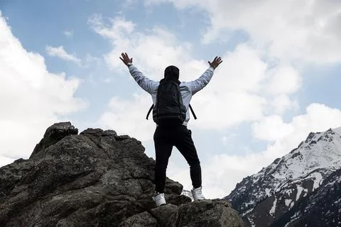 Guy with a travel backpack on the top of a boulder. the concept of achieving  Stock Photos