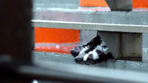Guy tries to keep cleats dry as rain falls on them in slow motion. Stock Footage 48670242
