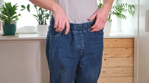 The guy trying on big jeans after losing weight. Man in oversized pants in Stock Footage 239448340