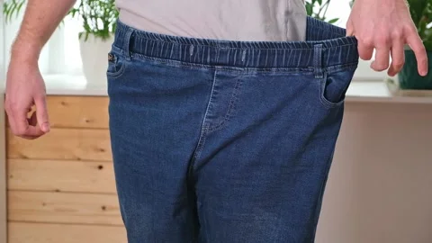 The guy trying on big jeans after losing weight. Man in oversized pants in Stock Footage 239448521