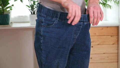The guy trying on big jeans after losing weight. Man in oversized pants in Stock Footage 239817116