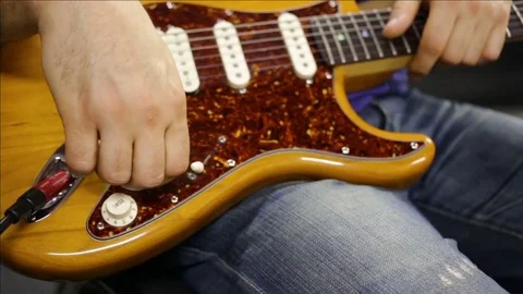 The guy turns the knob on the guitar changes the sound. Close-up of the body of  Stock Footage 83558044