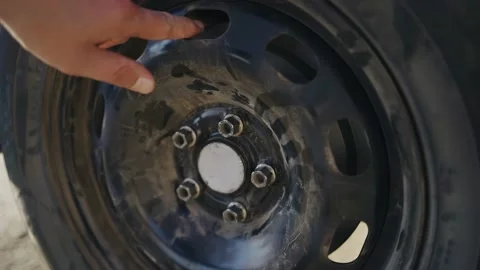 The guy turns the wheel of the car he is repairing with his hand Stock Footage 156002520