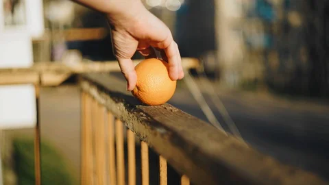 The guy twirls an orange on the edge of the balcony Stock Footage 129525579