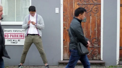 Guy types on the smartphone in a pretty corner of London Stock Footage 85300281