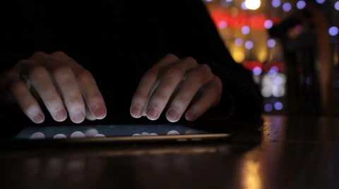 A guy types on a tablet in cafe in low light at beautiful bokeh background Stock Footage 47770892