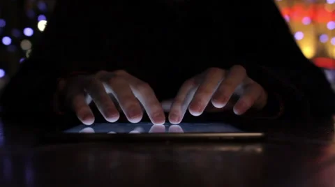 A guy types on a tablet in cafe in low light at beautiful bokeh background Video stock 47770920