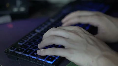 Guy typing on a keyboard with blue backlight Stock Footage 158856290