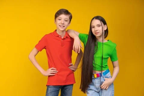 Guy und Mädchen in hellen T-Shirts auf gelbem Hintergrund Mädchen legte ih. Stock Photos