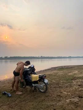 Guy in underwears getting dresse next to his motorbikes, next to a lake, Th.. Stock Photos