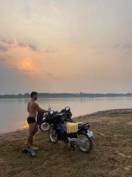 Guy in underwears getting dresse next to his motorbikes, next to a lake, Th.. Stock Photos