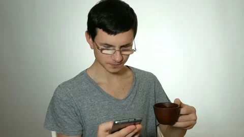 Guy uses a smartphone and drinks coffee Stock Footage 91003395