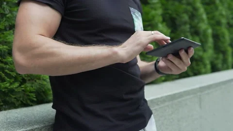 The guy uses the tablet on the street, only hands are visible 動画素材 113405235