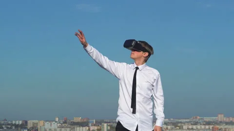Guy uses a virtual reality glasses on the backfound of sky Stock Footage 96510396